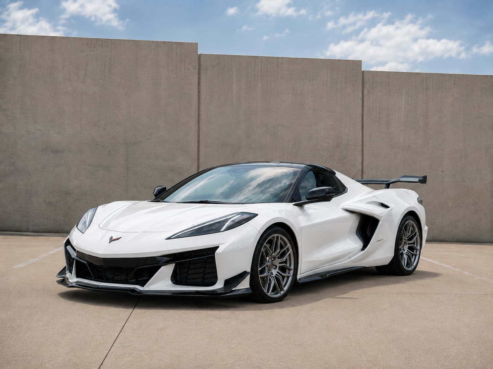 A white Corvette parked against a concrete wall