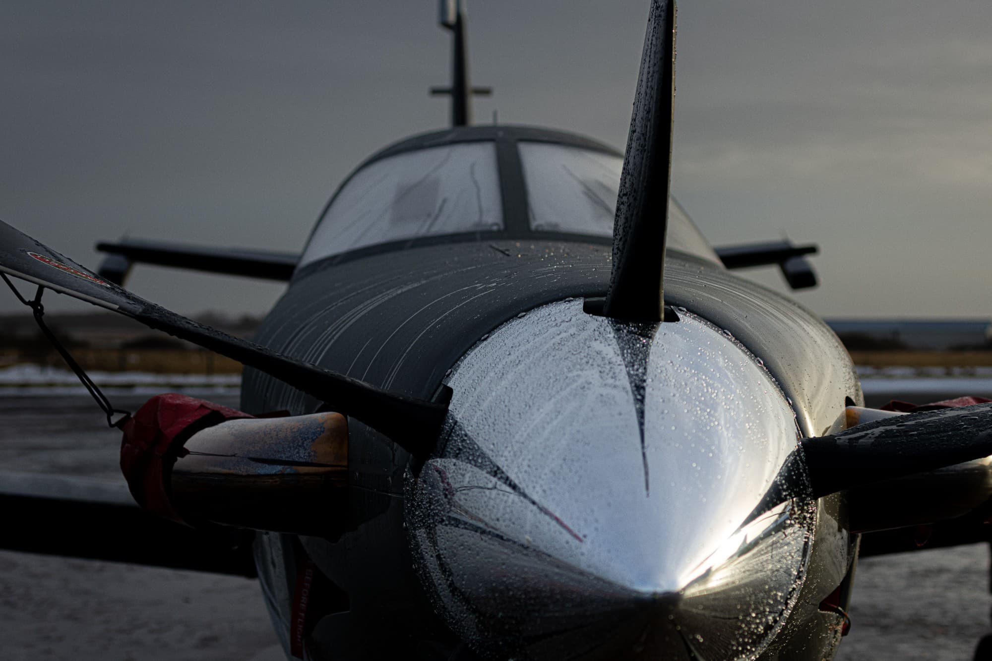 Aircraft nose and propeller with rain beads on the cowling, on a winter ramp