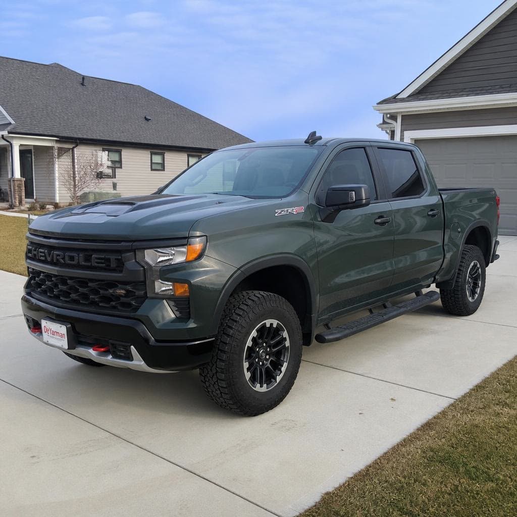 A dark green Chevrolet Silverado in a new driveway.