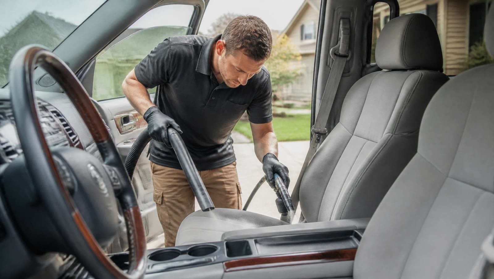 A detailer vacuuming the interior of a family SUV.